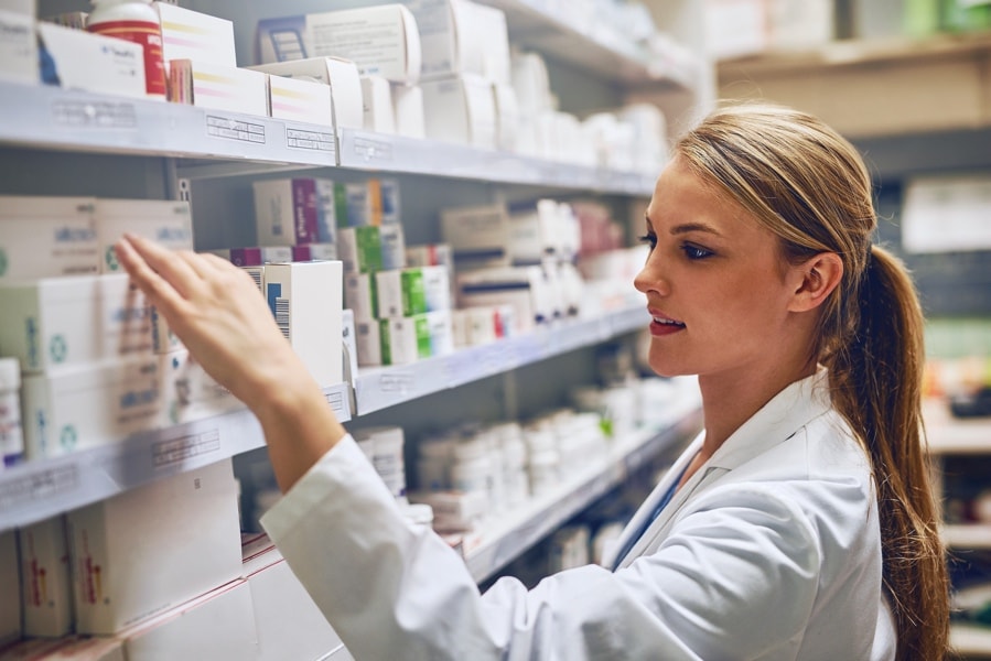 Pharmacist overlooking stock on a shelf